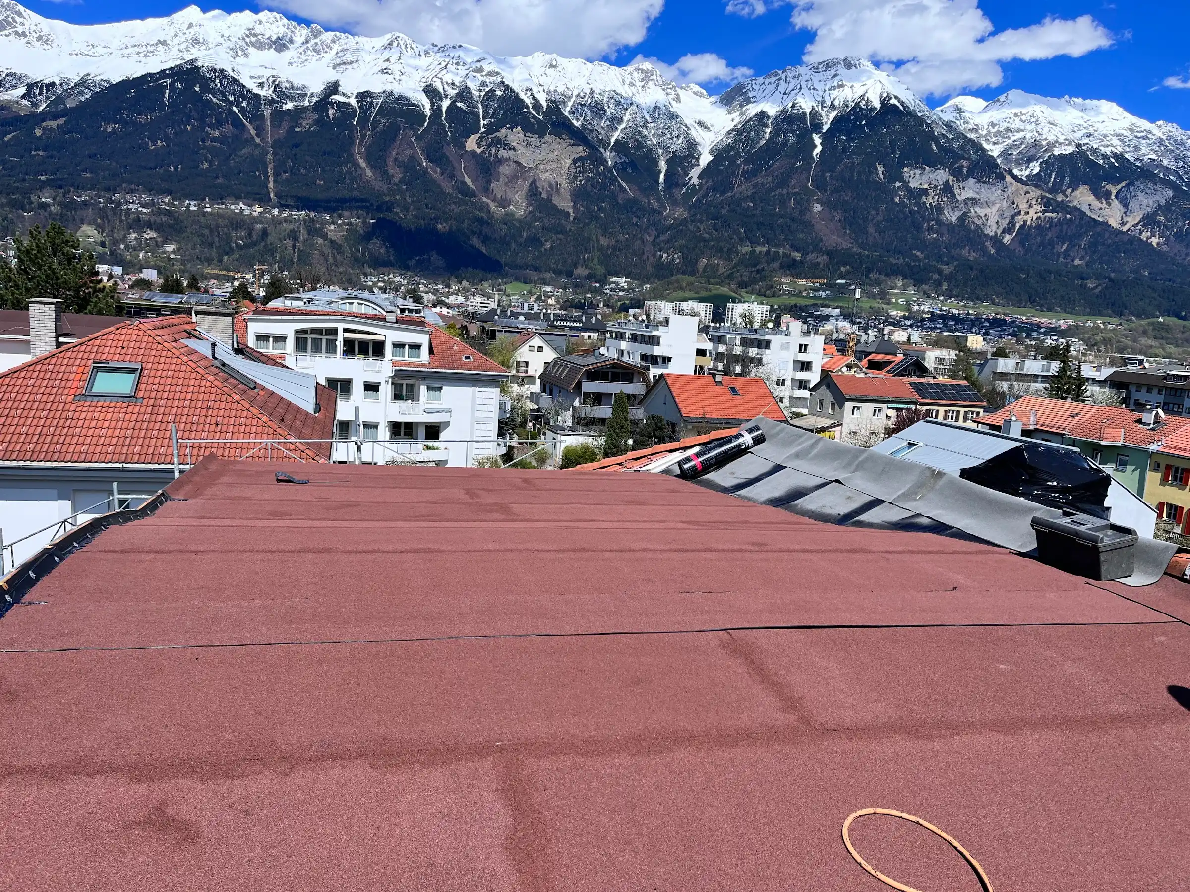 Flachdach mit roter Bitumenabdichtung, im Hintergrund die Nordkette