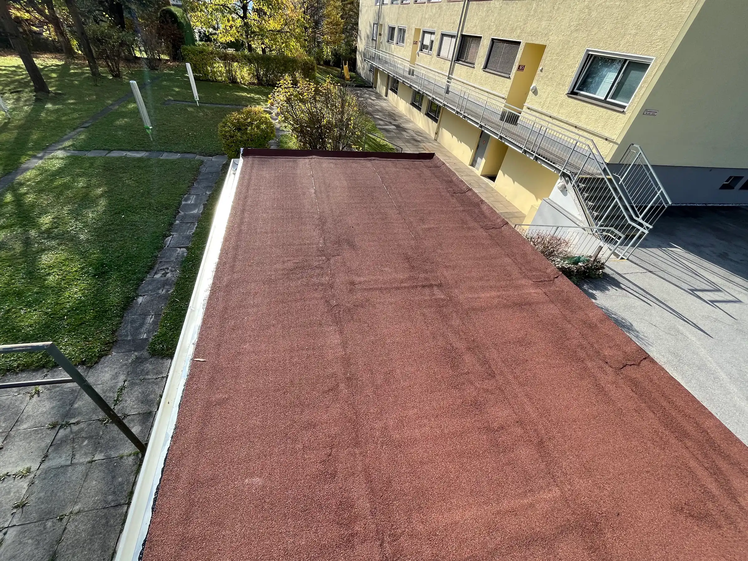 Flachdach einer Wohnanlage mit neuer roter Bitumenabdichtung